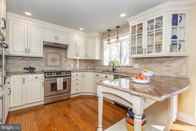 kitchen with sink, light stone counters, decorative light fixtures, appliances with stainless steel finishes, and kitchen peninsula