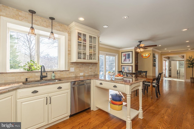 kitchen with sink, dishwasher, hardwood / wood-style floors, hanging light fixtures, and light stone counters