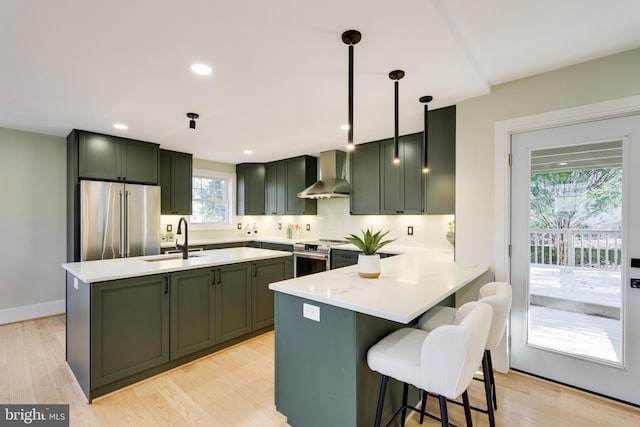 kitchen featuring appliances with stainless steel finishes, tasteful backsplash, sink, hanging light fixtures, and wall chimney exhaust hood