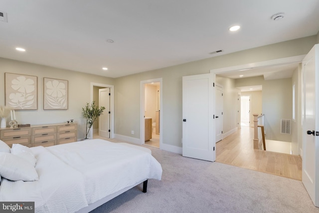 bedroom featuring connected bathroom and light colored carpet