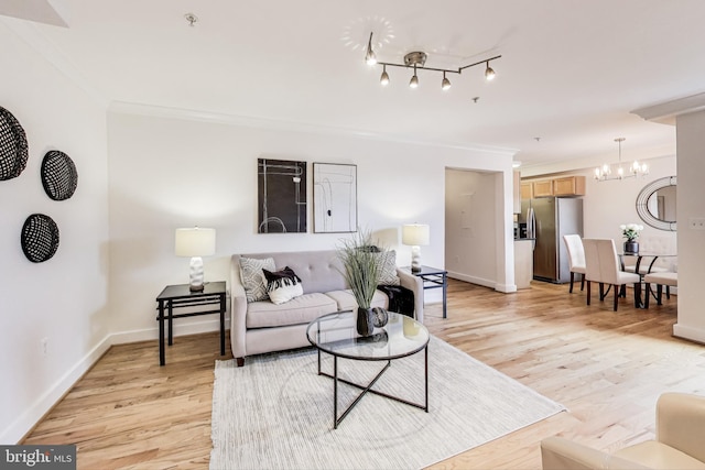 living room with an inviting chandelier, ornamental molding, and light hardwood / wood-style floors