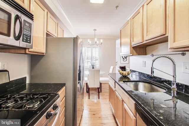 kitchen featuring crown molding, appliances with stainless steel finishes, decorative light fixtures, and dark stone counters