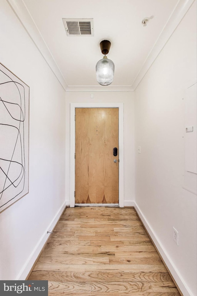 doorway with ornamental molding and light hardwood / wood-style floors