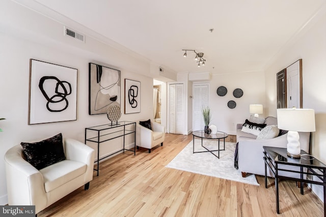 living room with ornamental molding, track lighting, and light wood-type flooring