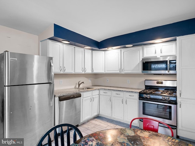 kitchen with sink, white cabinetry, light hardwood / wood-style flooring, stainless steel appliances, and light stone countertops