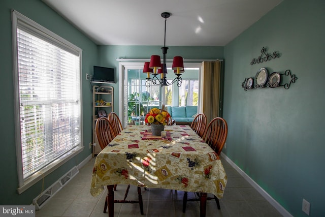 dining space featuring a notable chandelier, a healthy amount of sunlight, and tile patterned floors
