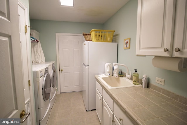 clothes washing area featuring light tile patterned flooring, cabinets, separate washer and dryer, and sink