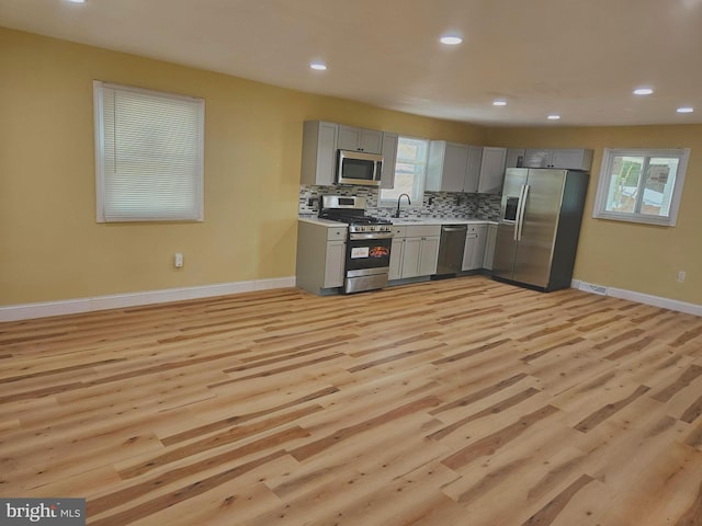 kitchen featuring sink, gray cabinets, appliances with stainless steel finishes, tasteful backsplash, and light hardwood / wood-style floors