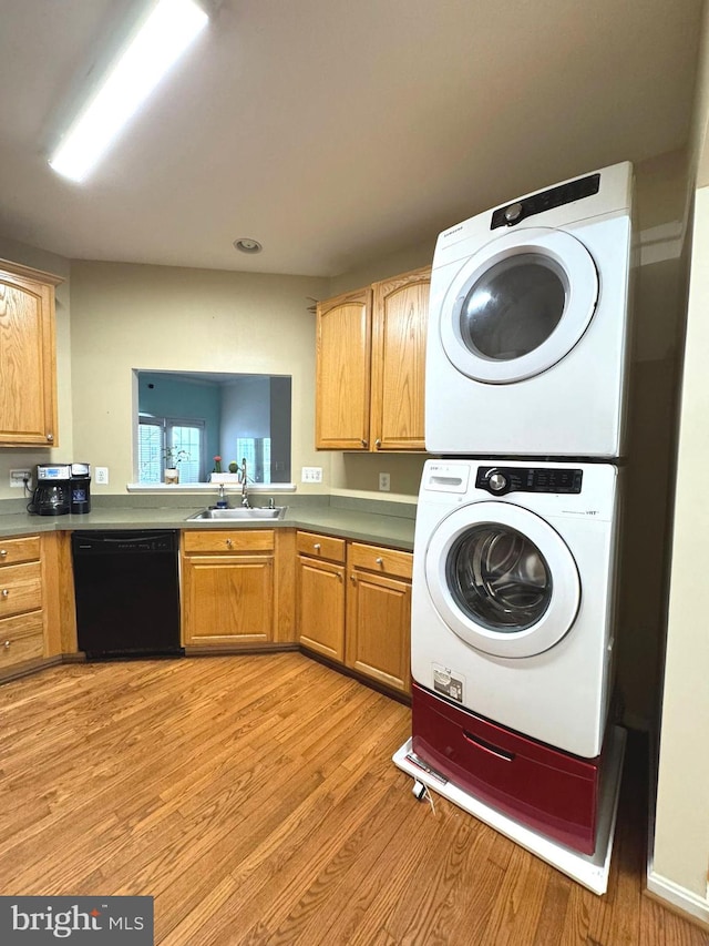 washroom featuring stacked washer / dryer, sink, and light hardwood / wood-style floors