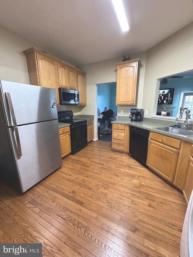 kitchen featuring sink, light hardwood / wood-style flooring, and black appliances