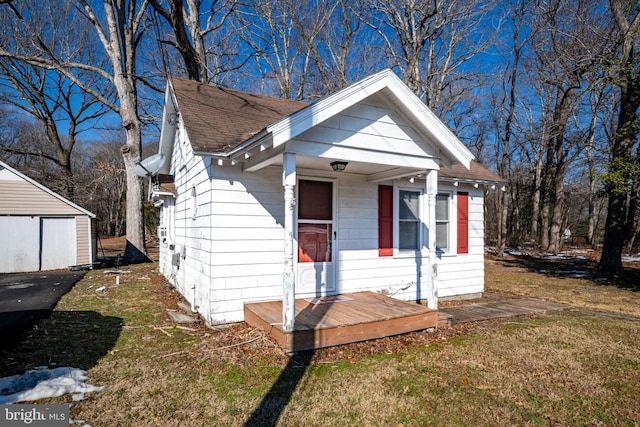 bungalow featuring an outbuilding and a front lawn