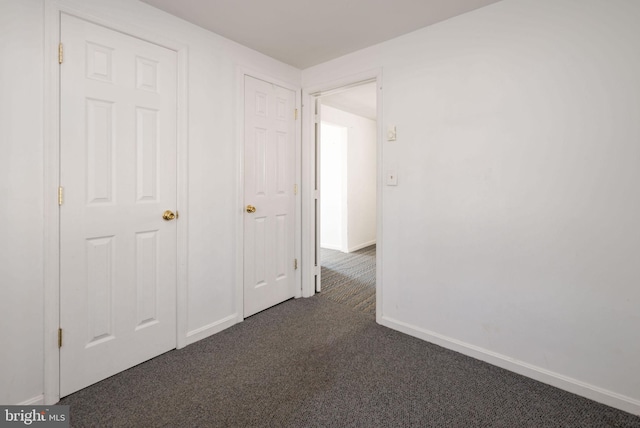 corridor featuring dark colored carpet