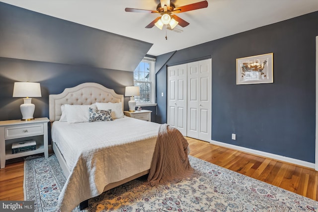 bedroom featuring wood finished floors, a ceiling fan, baseboards, vaulted ceiling, and a closet