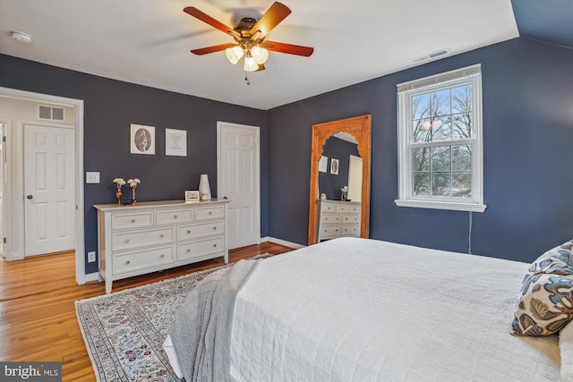 bedroom featuring ceiling fan, light wood-type flooring, visible vents, and baseboards