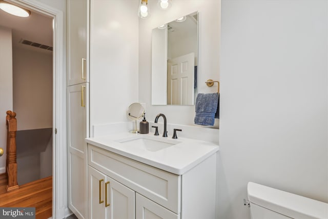 bathroom featuring toilet, vanity, and visible vents