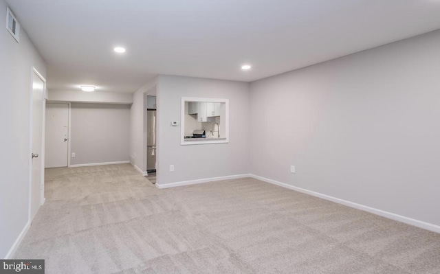 empty room with recessed lighting, light colored carpet, visible vents, a sink, and baseboards