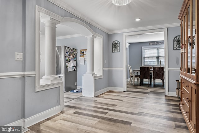 entryway with crown molding, light hardwood / wood-style floors, and decorative columns