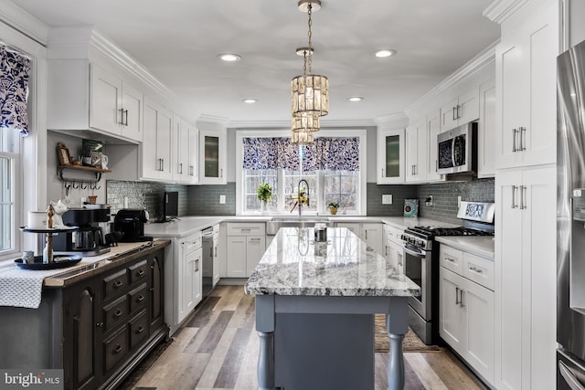 kitchen with stainless steel appliances, white cabinetry, a kitchen island, and ornamental molding