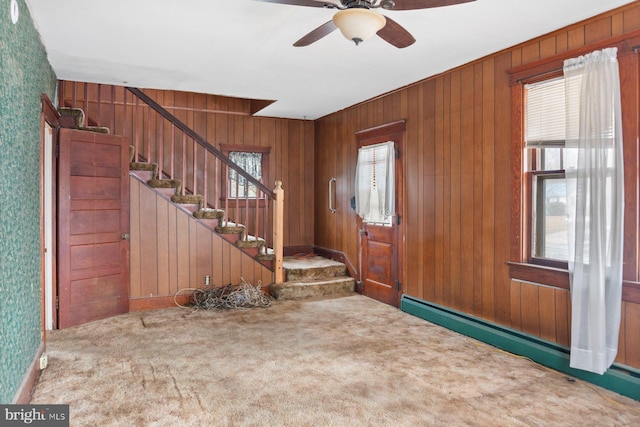 carpeted foyer entrance featuring ceiling fan, wood walls, and a baseboard heating unit