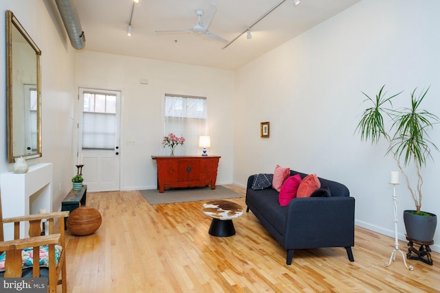 living room with ceiling fan, rail lighting, and light hardwood / wood-style floors