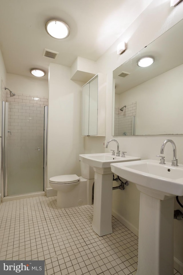 bathroom featuring tile patterned floors, toilet, and a shower with shower door