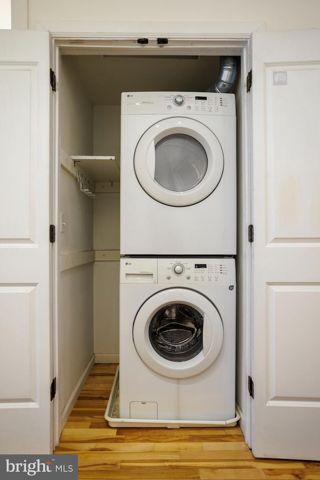 clothes washing area with stacked washer and dryer and light wood-type flooring