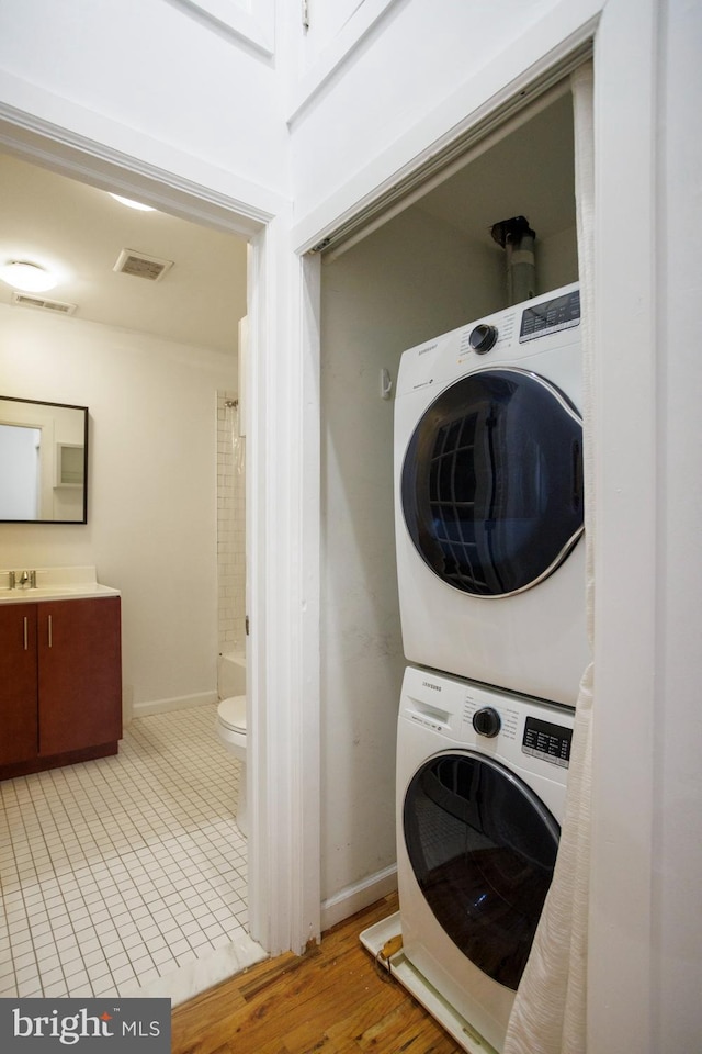 laundry area featuring stacked washer / drying machine and light hardwood / wood-style floors