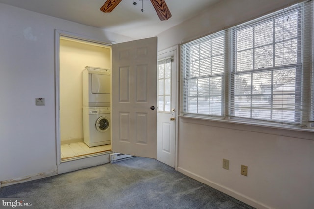 interior space featuring stacked washer and clothes dryer, carpet, and ceiling fan