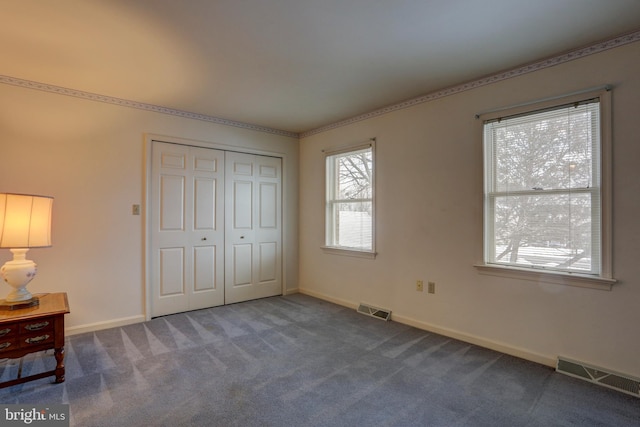 unfurnished bedroom featuring dark carpet and a closet