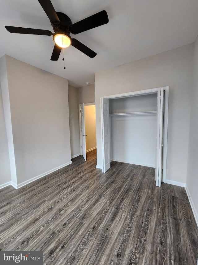 unfurnished bedroom featuring dark wood-type flooring, ceiling fan, and a closet