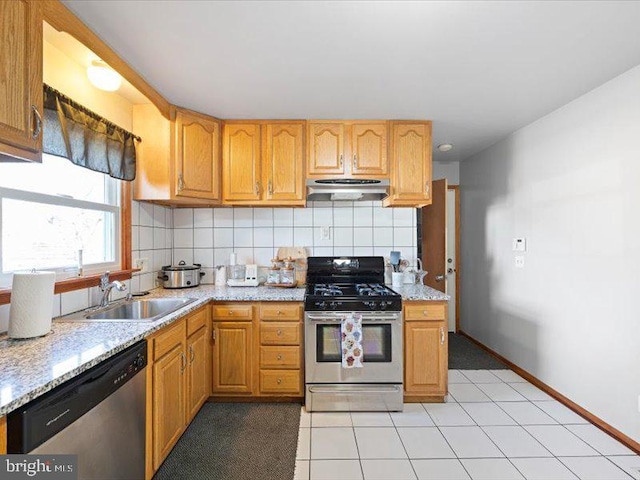 kitchen featuring light tile patterned flooring, appliances with stainless steel finishes, sink, decorative backsplash, and light stone counters