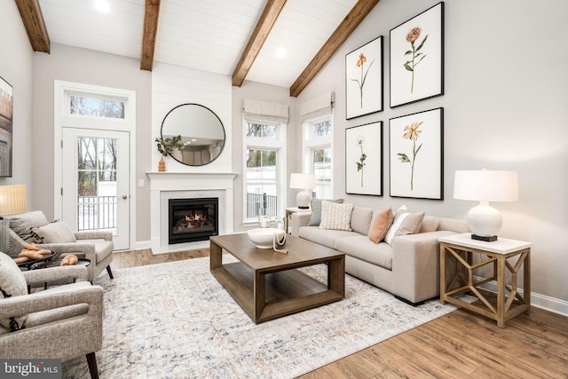 living room with beam ceiling, a wealth of natural light, and light hardwood / wood-style flooring