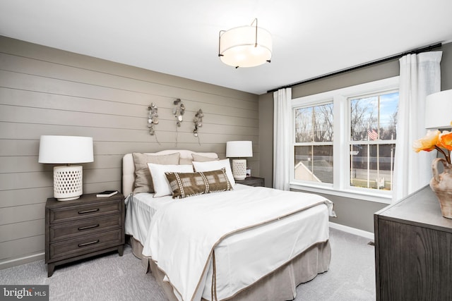 carpeted bedroom featuring multiple windows and wood walls