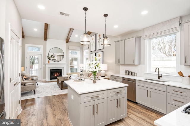 kitchen featuring sink, gray cabinets, hanging light fixtures, stainless steel dishwasher, and beamed ceiling