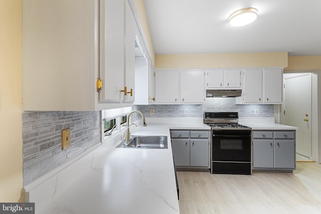 kitchen with gray cabinetry, sink, black range with gas stovetop, and decorative backsplash