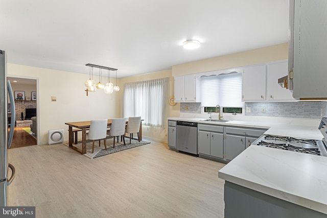 kitchen featuring sink, gray cabinetry, appliances with stainless steel finishes, pendant lighting, and backsplash