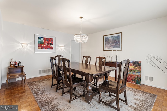 dining space with parquet flooring and a chandelier