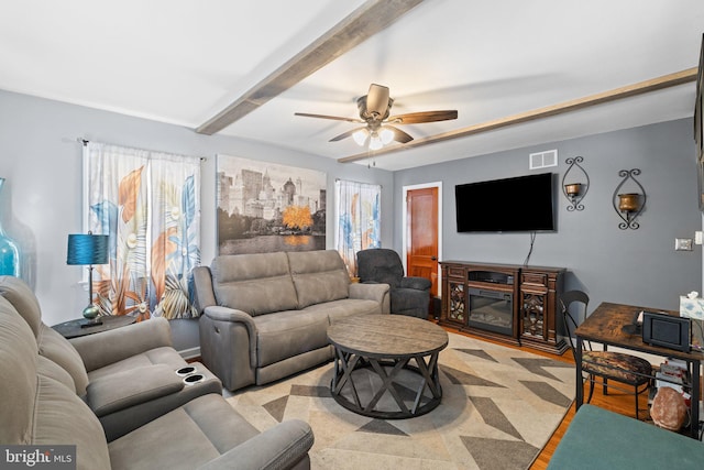 living room featuring ceiling fan, light hardwood / wood-style floors, and beamed ceiling