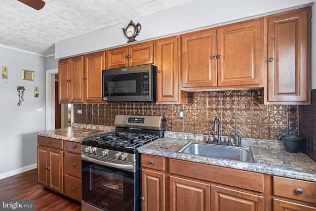 kitchen featuring dark wood-type flooring, stainless steel gas range, sink, and light stone counters