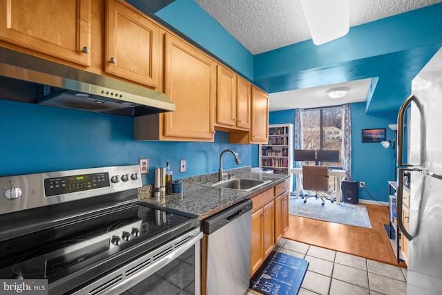 kitchen featuring sink, a textured ceiling, light tile patterned floors, dark stone countertops, and stainless steel appliances