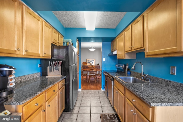 kitchen with sink, stainless steel appliances, dark stone counters, and a textured ceiling