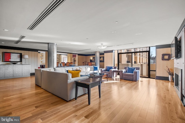 living room with expansive windows and light hardwood / wood-style floors