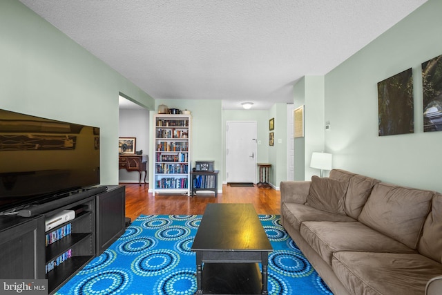 living room featuring dark wood-type flooring and a textured ceiling