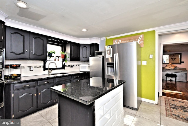 kitchen with a kitchen island, sink, dark stone countertops, ornamental molding, and stainless steel refrigerator with ice dispenser