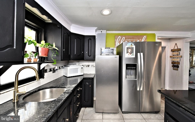 kitchen featuring ornamental molding, stainless steel fridge, sink, and dark stone countertops