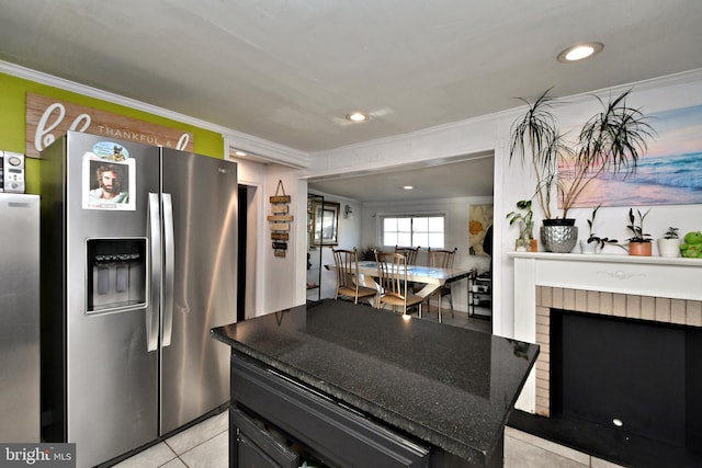 kitchen with crown molding, a center island, stainless steel fridge with ice dispenser, a brick fireplace, and light tile patterned floors