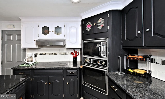 kitchen featuring white cabinetry, ornamental molding, dark stone counters, decorative backsplash, and black appliances