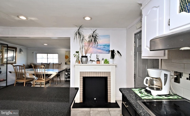 kitchen with ornamental molding, a brick fireplace, light tile patterned floors, and white cabinets