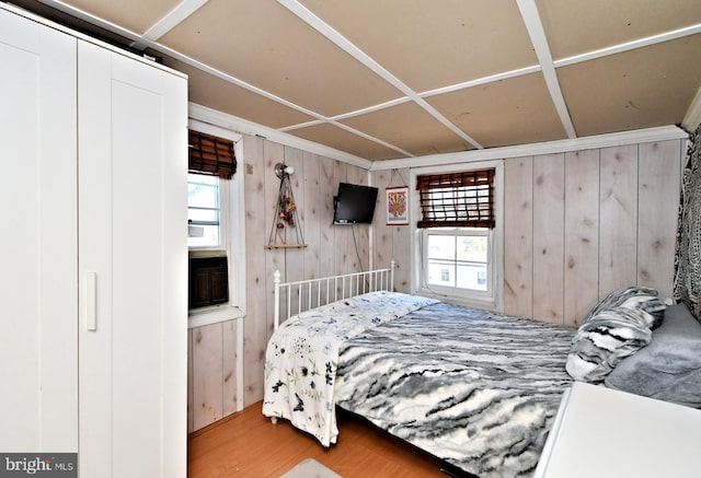 bedroom with hardwood / wood-style floors, multiple windows, and wood walls