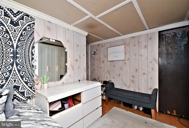 bedroom featuring ornamental molding, wooden walls, and light hardwood / wood-style flooring